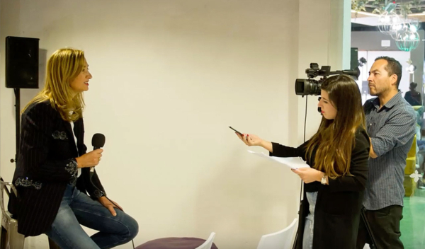 Presentadora de televisión en un estudio siendo grabada por los operadores de cámara.